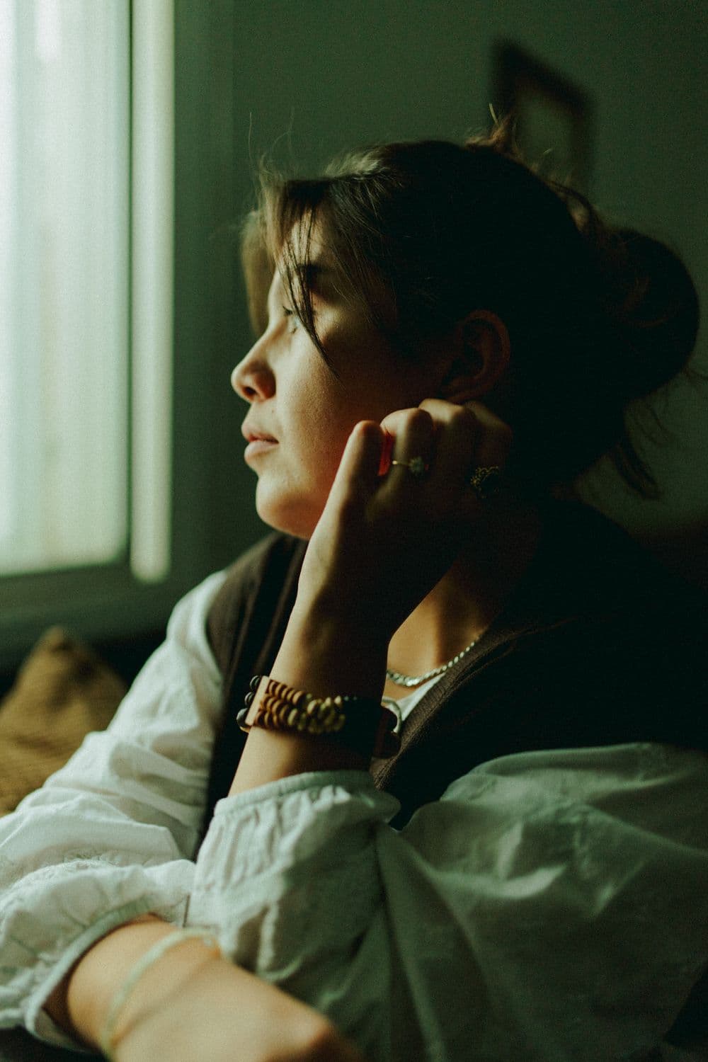 A woman quietly reflecting beside a window in soft daylight