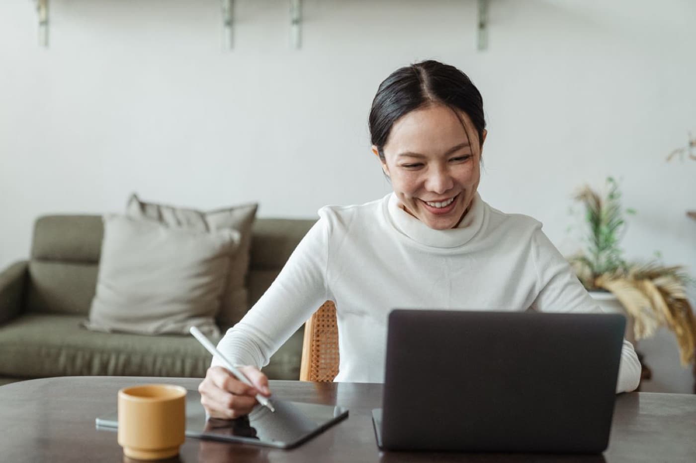 A woman smiling during an online session at her dining table